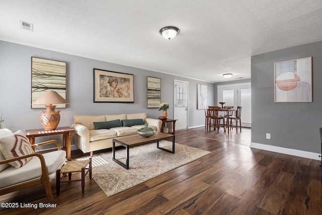 living room featuring dark wood-style floors, crown molding, visible vents, and baseboards