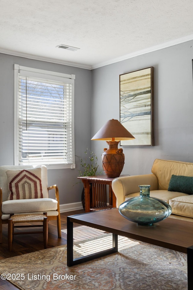 sitting room featuring baseboards, visible vents, ornamental molding, wood finished floors, and a textured ceiling