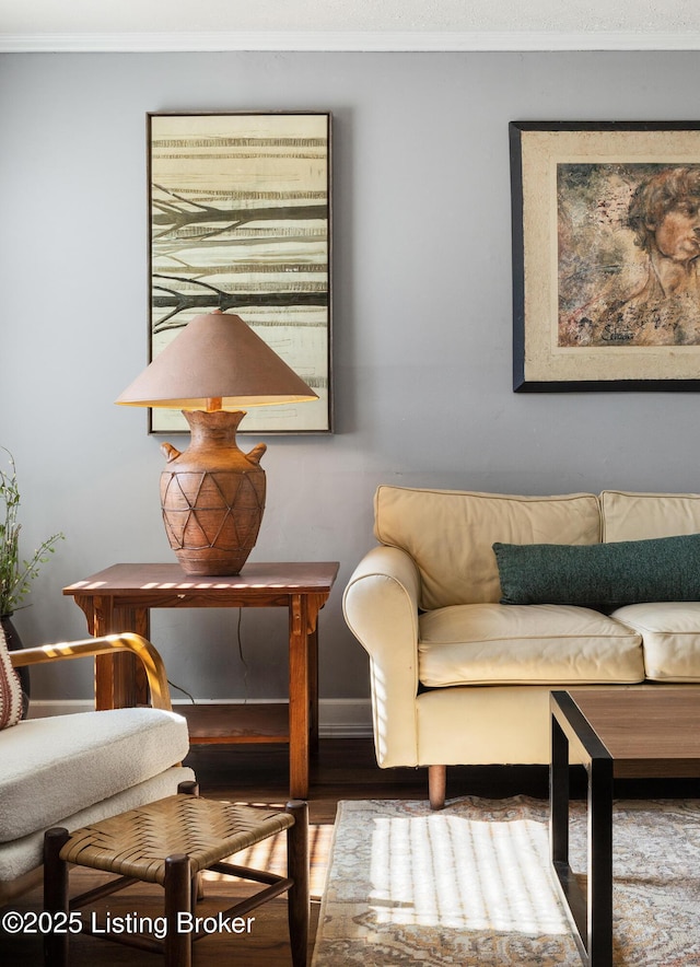 sitting room with baseboards, wood finished floors, and crown molding