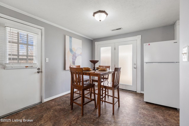 dining space with ornamental molding, visible vents, a textured ceiling, and baseboards