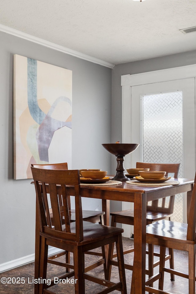 dining room featuring baseboards, a textured ceiling, visible vents, and crown molding