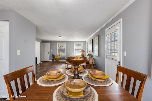 dining space featuring crown molding, a textured ceiling, baseboards, and wood finished floors