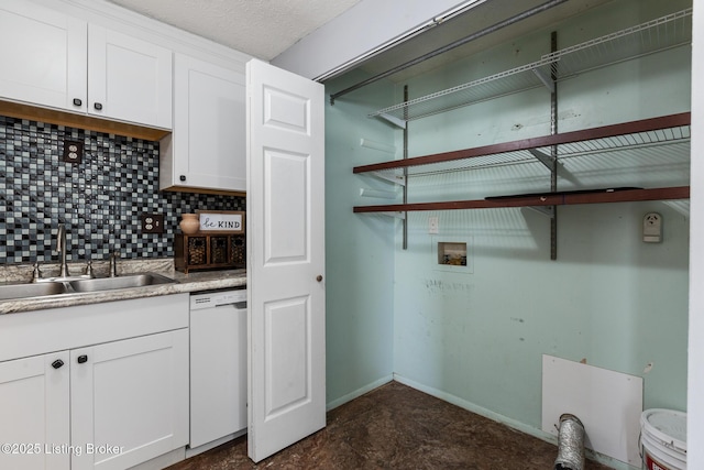 laundry area featuring a textured ceiling, hookup for a washing machine, laundry area, a sink, and baseboards