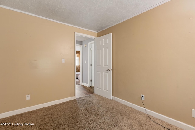 spare room with carpet, crown molding, a textured ceiling, and baseboards