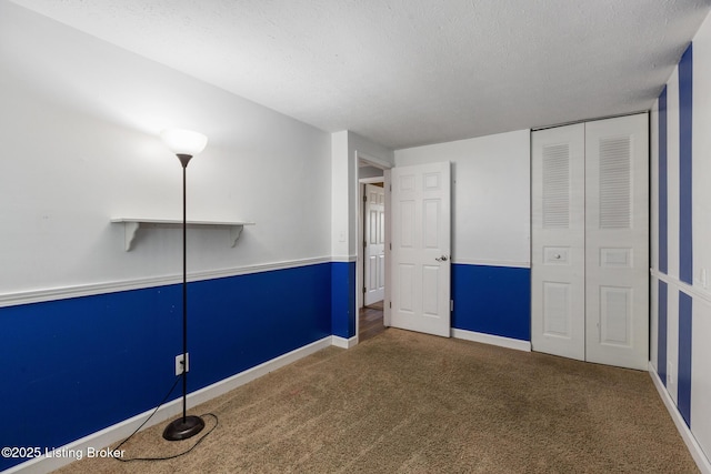 unfurnished bedroom with a textured ceiling, carpet floors, a closet, and baseboards