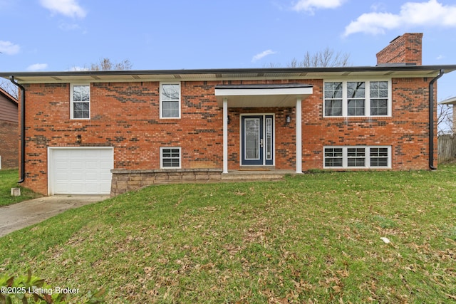 bi-level home with a front yard, concrete driveway, a chimney, an attached garage, and brick siding