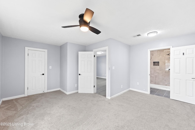 unfurnished bedroom featuring baseboards, visible vents, ensuite bath, ceiling fan, and carpet flooring