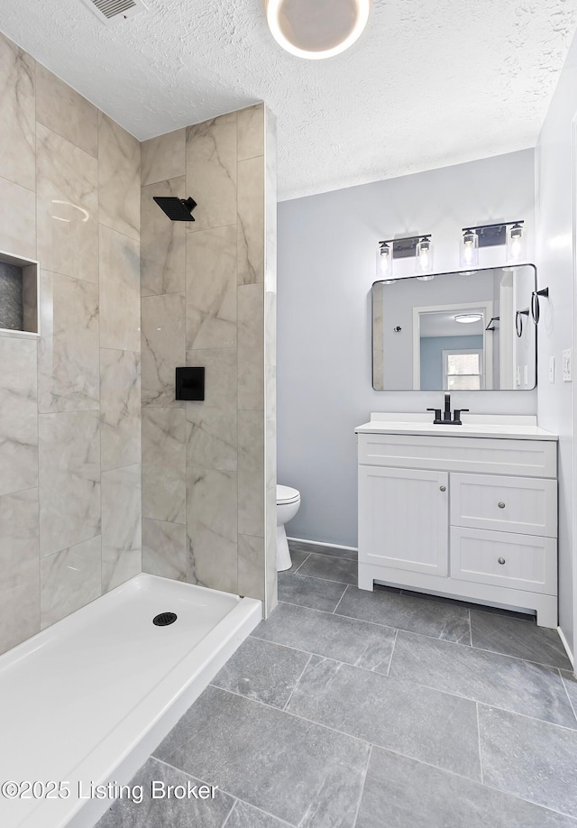 full bath with baseboards, toilet, a textured ceiling, vanity, and a shower stall