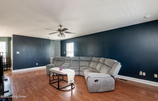 living area featuring ceiling fan, visible vents, baseboards, and wood finished floors