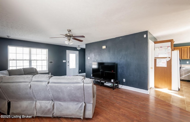 living room featuring ceiling fan, baseboards, and wood finished floors