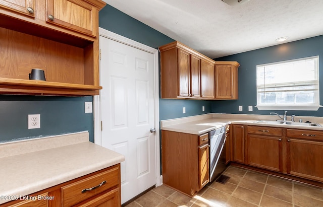 kitchen featuring brown cabinets, light tile patterned floors, light countertops, a sink, and dishwasher