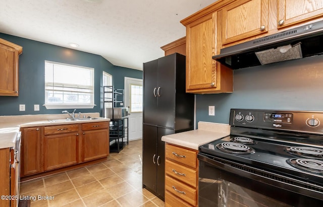 kitchen with light countertops, a sink, under cabinet range hood, and black appliances