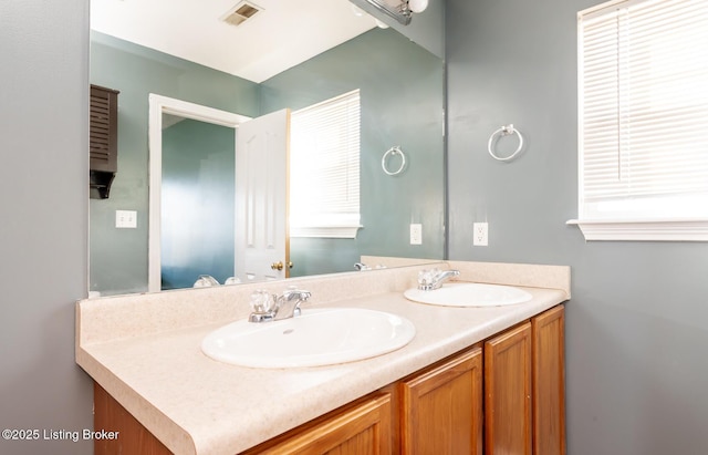 bathroom with double vanity, visible vents, and a sink