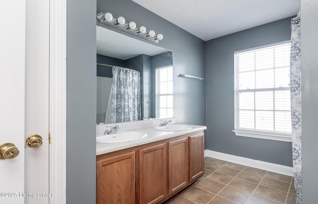 bathroom with double vanity, tile patterned flooring, baseboards, and a sink