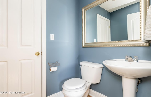 bathroom featuring a sink, toilet, and baseboards