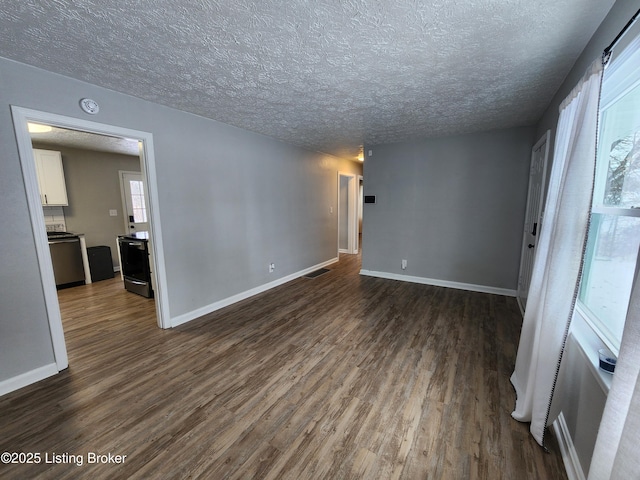 empty room with dark wood-style floors, baseboards, visible vents, and a textured ceiling