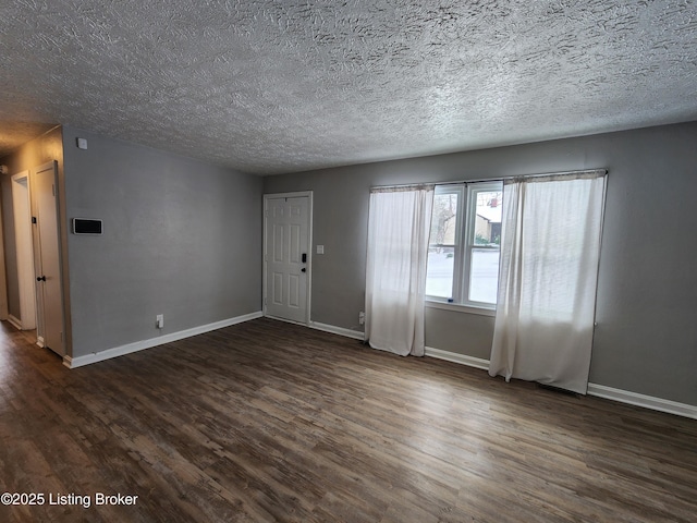 interior space with a textured ceiling, dark wood-style flooring, and baseboards