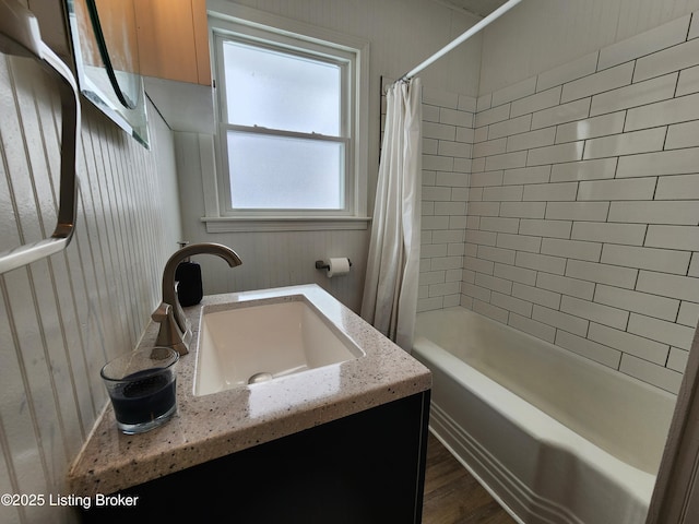 bathroom featuring wooden walls, shower / bath combo, wood finished floors, and vanity