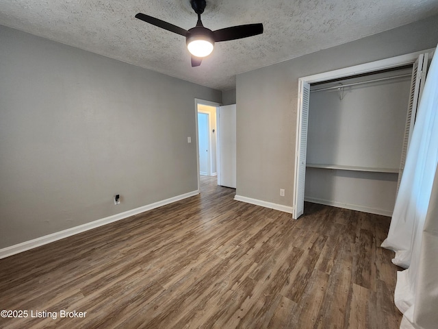 unfurnished bedroom with a closet, a ceiling fan, a textured ceiling, wood finished floors, and baseboards