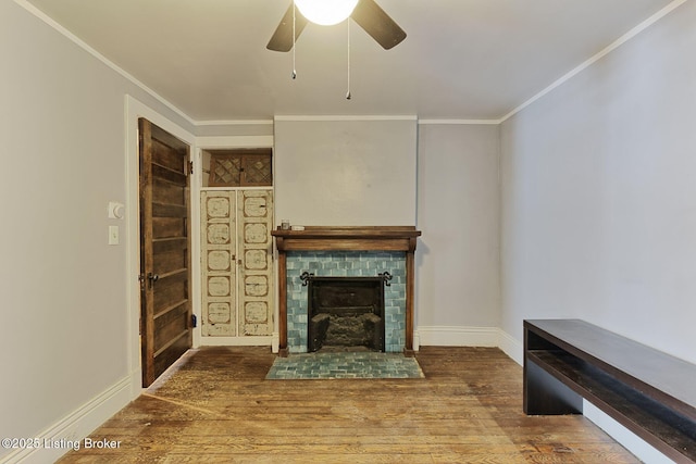 unfurnished living room featuring ceiling fan, ornamental molding, a brick fireplace, and wood finished floors