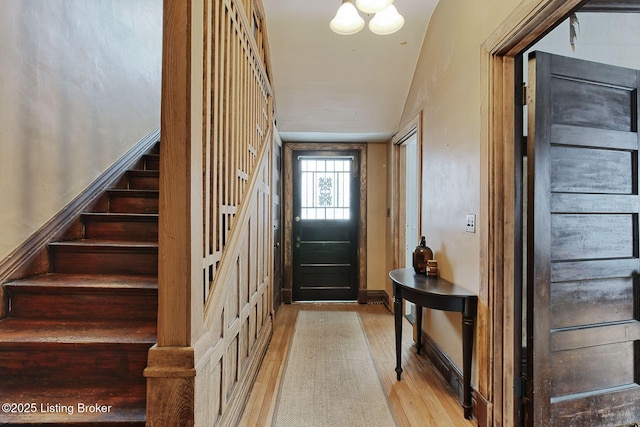 foyer entrance with baseboards, light wood finished floors, and stairs