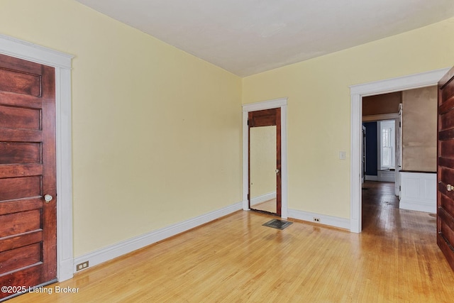 unfurnished room featuring light wood-style flooring, visible vents, and baseboards