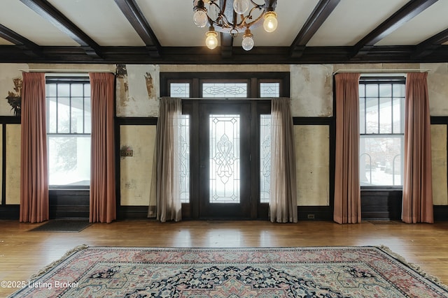 entryway with a wealth of natural light, beam ceiling, a chandelier, and wood finished floors