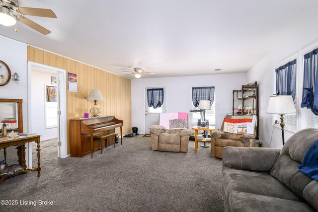 carpeted living room with wooden walls and a ceiling fan