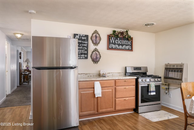 kitchen with visible vents, baseboards, wood finished floors, appliances with stainless steel finishes, and heating unit