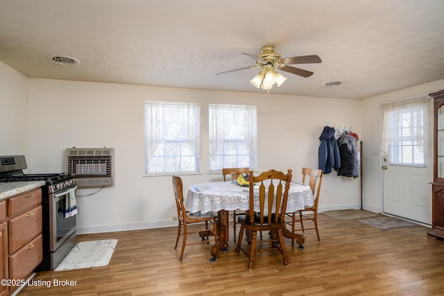 dining room featuring heating unit, light wood-style flooring, a ceiling fan, and visible vents