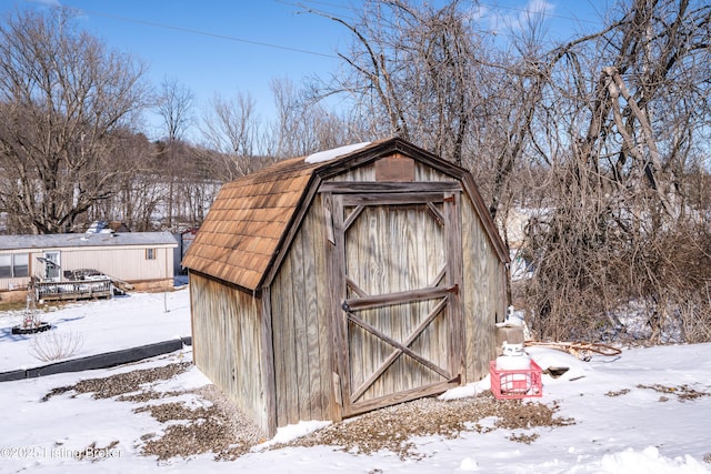 snow covered structure with an outbuilding