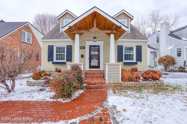 view of front of property with a shingled roof and brick siding