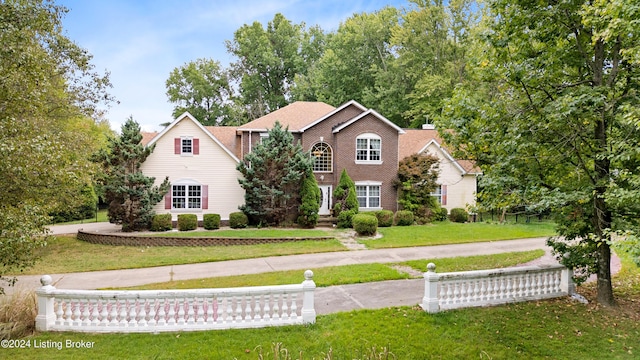 view of front of home featuring brick siding, a chimney, and a front lawn