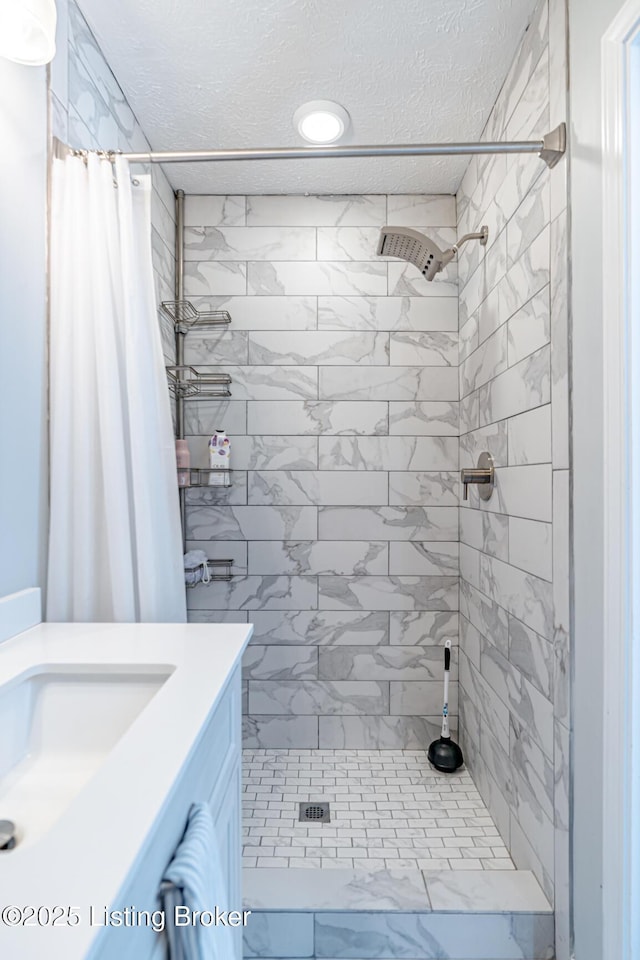 bathroom with a shower stall, a textured ceiling, and vanity