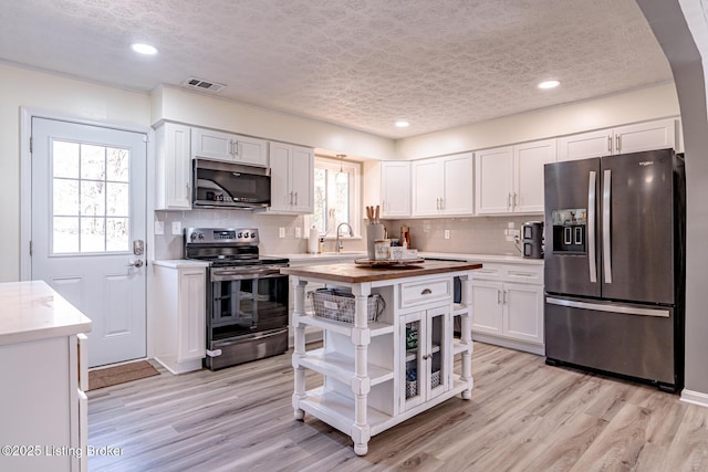 kitchen featuring appliances with stainless steel finishes, light wood-style floors, and white cabinets