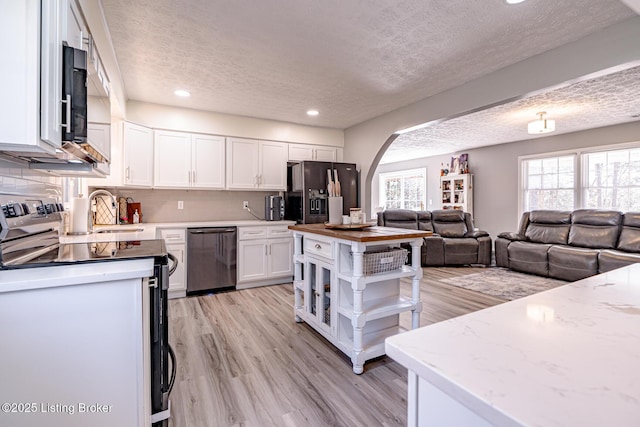 kitchen featuring dishwashing machine, electric range, black fridge with ice dispenser, white cabinetry, and open floor plan