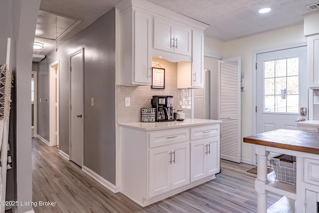 kitchen featuring light wood-type flooring, decorative backsplash, and white cabinets