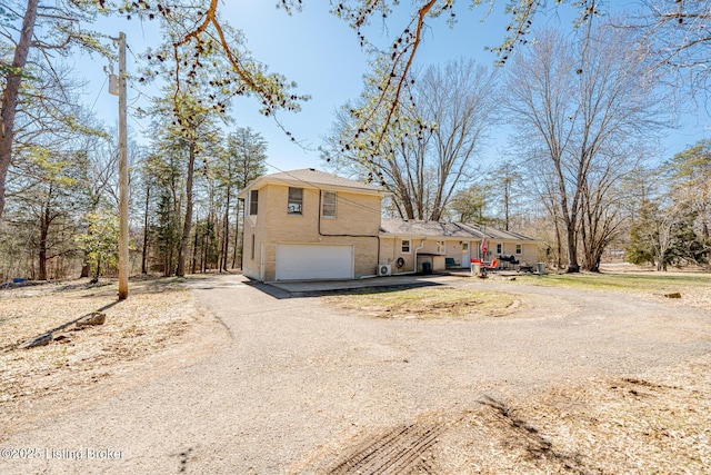 view of front of house featuring driveway, an attached garage, and brick siding