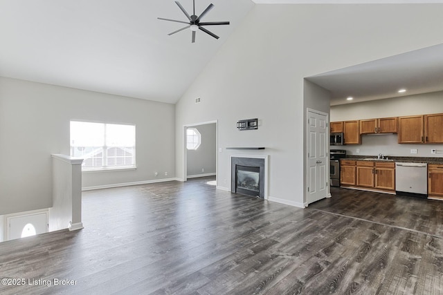 unfurnished living room featuring dark wood-style floors, a premium fireplace, a sink, and baseboards