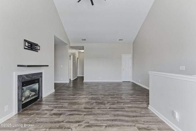 unfurnished living room with a premium fireplace, high vaulted ceiling, and dark wood finished floors