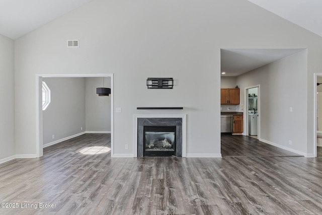 unfurnished living room featuring light wood-style flooring, a fireplace, visible vents, and baseboards