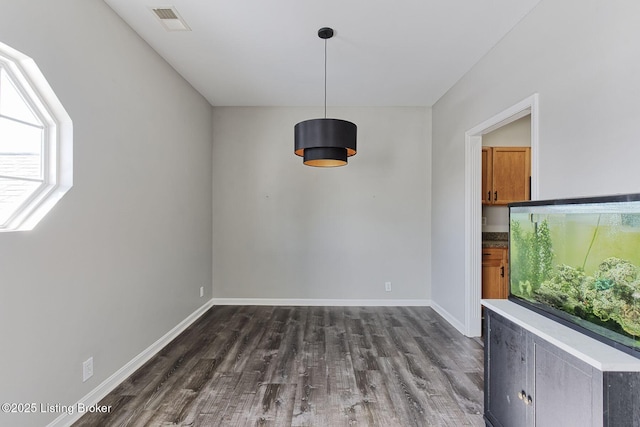 unfurnished dining area featuring dark wood finished floors, visible vents, and baseboards