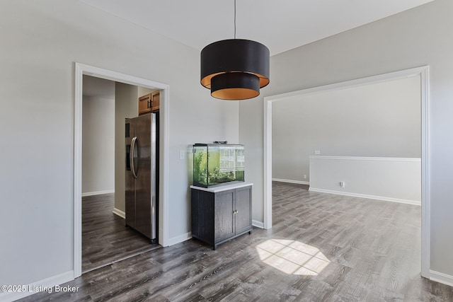 spare room with baseboards and dark wood-style flooring