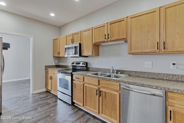 kitchen with recessed lighting, dark wood-type flooring, a sink, appliances with stainless steel finishes, and dark countertops