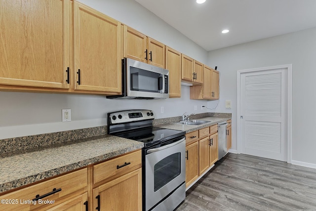 kitchen featuring recessed lighting, appliances with stainless steel finishes, light brown cabinets, a sink, and wood finished floors