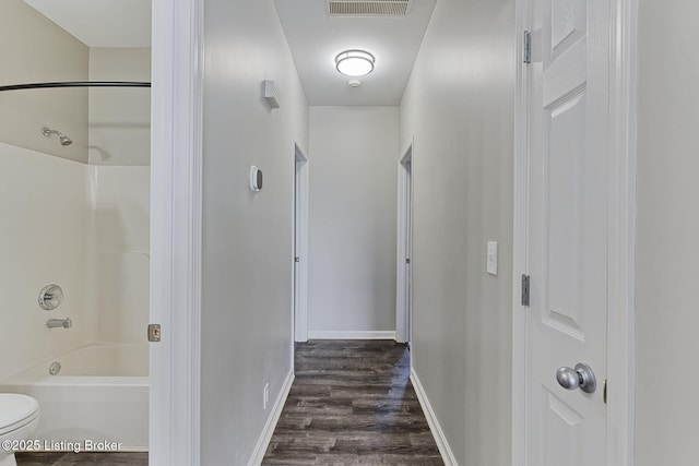 hall with visible vents, dark wood finished floors, and baseboards