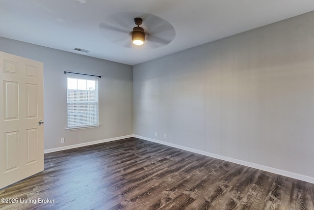 empty room featuring dark wood-style flooring, visible vents, ceiling fan, and baseboards