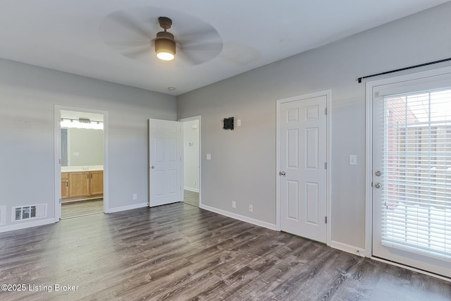 unfurnished bedroom featuring baseboards, connected bathroom, visible vents, and dark wood-type flooring