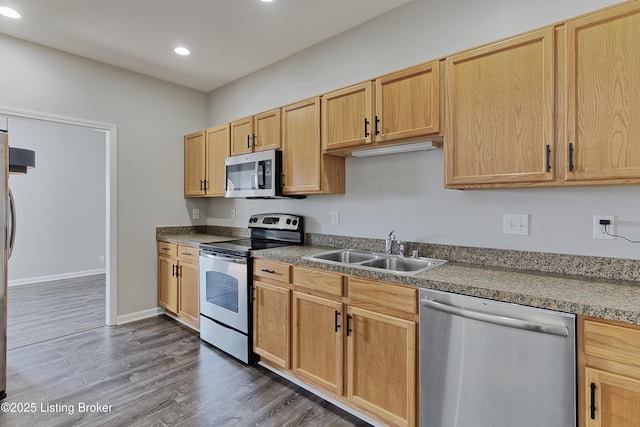 kitchen featuring dark wood finished floors, stainless steel appliances, dark countertops, recessed lighting, and a sink