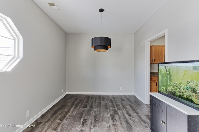 unfurnished dining area featuring dark wood-type flooring, visible vents, and baseboards